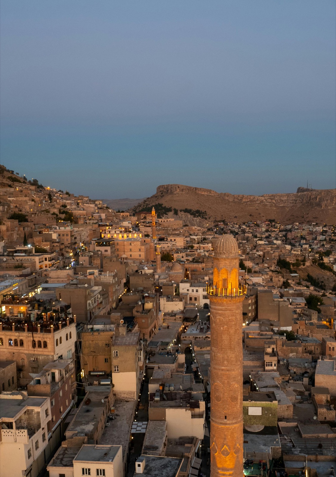 Mardin al crepuscolo con minareto illuminato e città di pietra sulla Mesopotamia